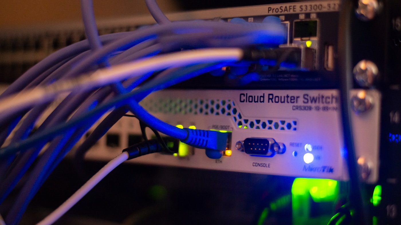 A rack of network switches with a tangle of blue Ethernet cables