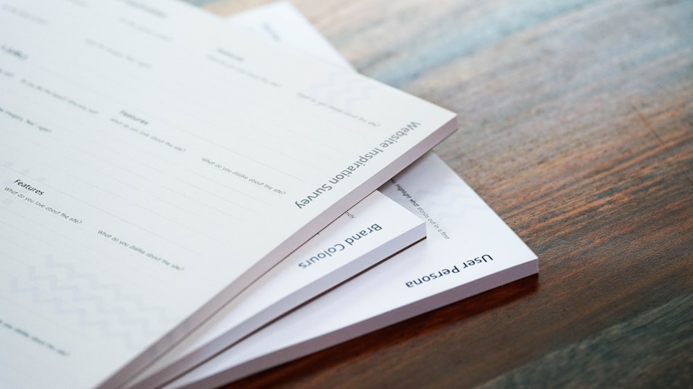 A tall stack of paper survey forms on a wooden table